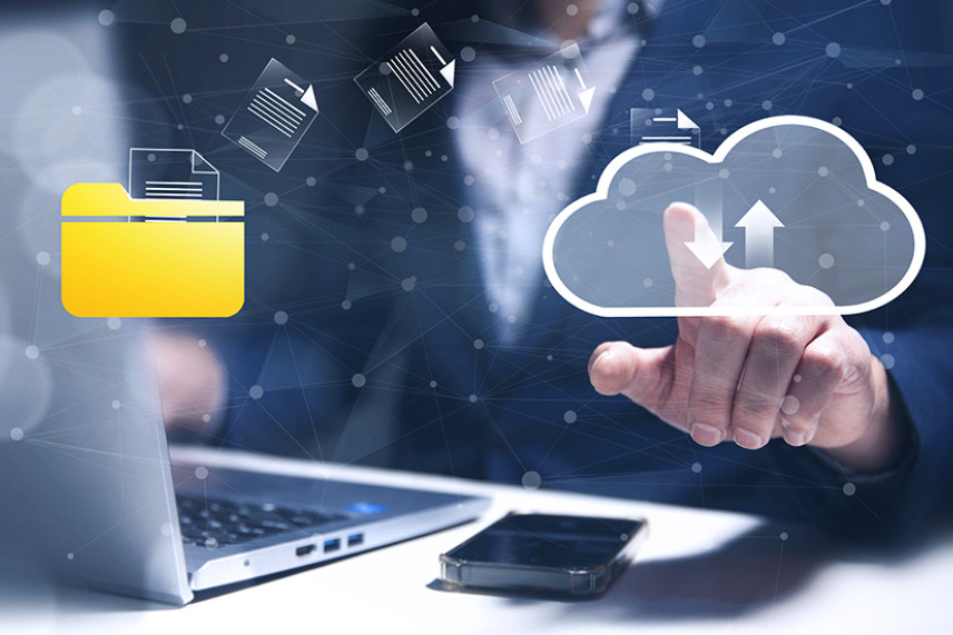 Käsi puudutamas pilveikoonile, kust liiguvad dokumendid digitaalsest kaustast pilve. Taustal võrgustik, esiplaanil sülearvuti ja telefon.