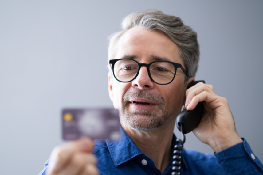 mees räägib telefoniga ja vaatab oma pangakaarti