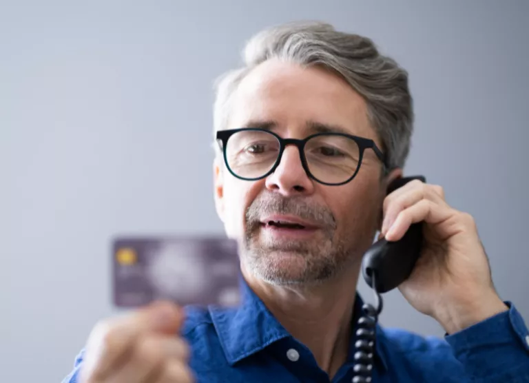 mees räägib telefoniga ja vaatab oma pangakaarti